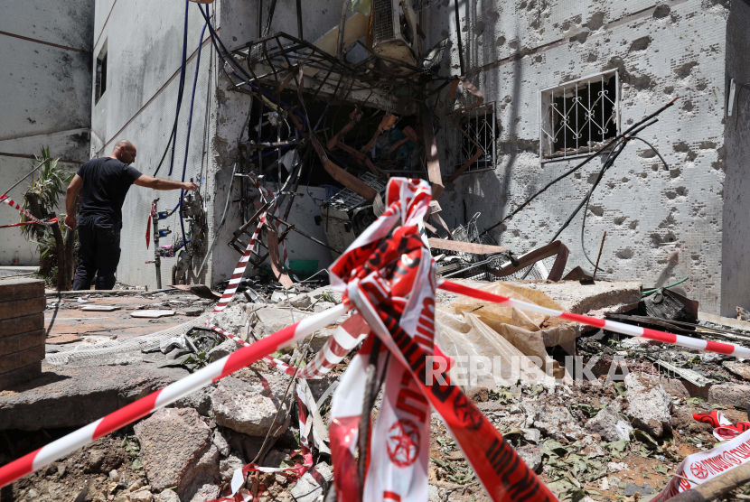 Orang Israel memeriksa bangunan yang rusak setelah dihantam oleh roket yang ditembakkan dari Jalur Gaza, di kota Ashdod, Israel, Selasa (18/5).