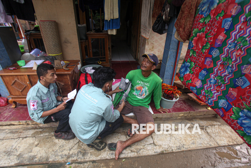 Petugas medis memeriksa kesehatan warga terdampak banjir bandang di Desa Curug Luhur, Sagaranten, Kabupaten Sukabumi, Ahad (8/12/2024). 