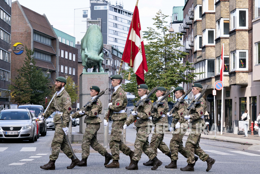  Tentara berbaris saat mereka membawa bendera Denmark melewati patung Cimbrer Bull di Aalborg, Denmark, Ahad 5 September 2021. Kementerian Pertahanan Denmark mengatakan negara Nordik itu akan berinvestasi sebesar 40 miliar crown atau 5,47 miliar dolar AS ke Angkatan Laut.
