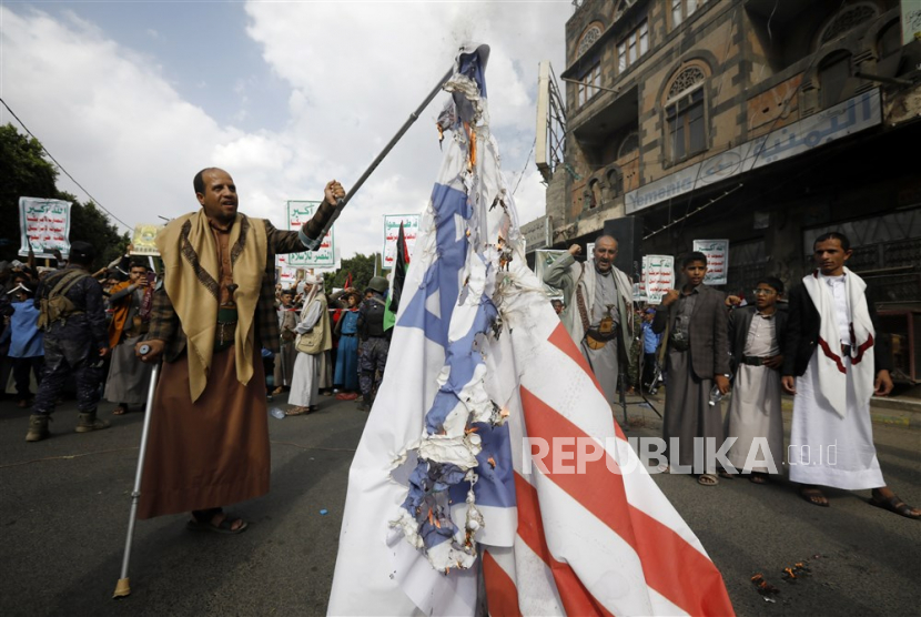 Warga Yaman menunjukan bendera Israel dan Amerika yang sudah rusak terbakar saat unjuk rasa anti-Israel  di Sanaa, Yaman, (4/7/2023)