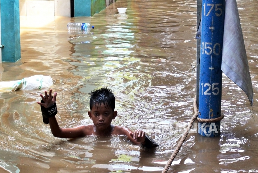 Seorang bocah berjalan melintasi banjir di kawasan Bidara Cina, Jakarta, Senin (10/10/2022). Badan Penanggulangan Bencana Daerah (BPBD) DKI Jakarta menyebutkan hingga Senin (10/10/2022) pukul 09.00 WIB sebanyak 68 rukun tetangga (RT) terendam banjir akibat luapan Sungai Ciliwung. 