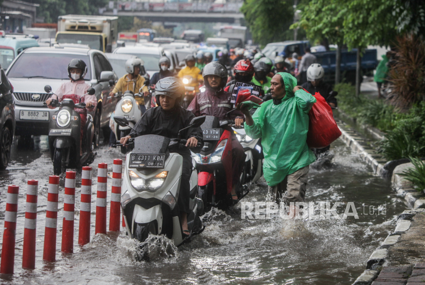 Sejumlah pengendara motor melewati genangan air di Jalan DI Pandjaitan, Jatinegara, Jakarta Timur, Senin (5/2/2024).