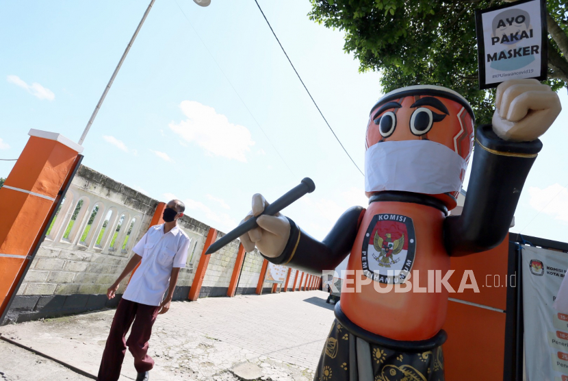 Karyawan melintas didekat patung maskot Pilkada Kota Blitar Si Kendang Memilih (Si Danglih) di kantor Komisi Pemilihan Umum Daerah (KPUD) Kota Blitar, Jawa Timur, Kamis (9/4/2020). KPUD Kota Blitar memanfaatkan patung maskot Pilkada Kota Blitar Si Danglih sebagai media kampanye ajakan memakai masker bagi masyarakat guna mendukung program pemerintah dalam menekan penyebaran COVID-19