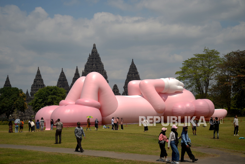Pengunjung melihat Boneka raksasa KAWS karya seniman Brian Donelly yang menjadi ikon seni rupa kontemporer menghiasi pelataran Candi Brahma, Komplek Candi Prambanan, Yogyakarta, Rabu (23/8/2023). 