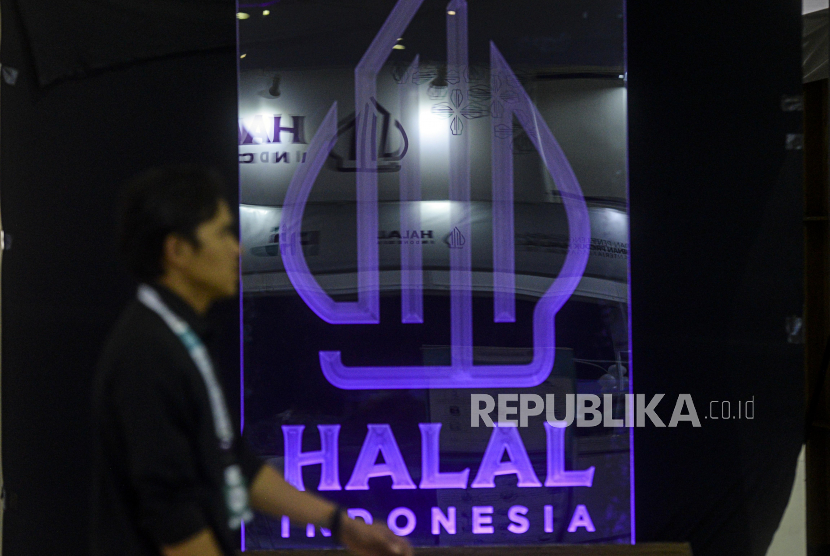 Pengunjung melintas di dekat logo halal saat Festival Halal Indonesia di Asrama Haji Pondok Gede, Jakarta, Rabu (14/12/2022). Indonesia menargetkan menjadi produsen makanan dan minuman halal nomor wahid dunia pada 2024.