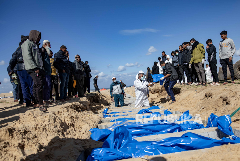 Petugas Kementerian Kesehatan Palestina mempersiapkan jenazah untuk pemakaman massal di kamp Rafah, selatan Jalur Gaza, Selasa (30/1/2024).