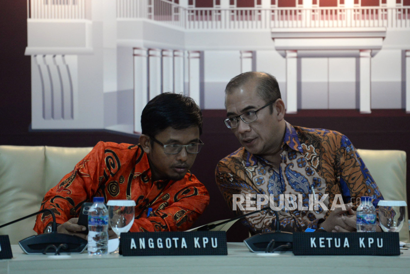 Ketua KPU Hasyim Asyari berbincang dengan anggota KPU Idham Holik sebelum memberikan keterangan di Gedung KPU, Jakarta, Jumat (18/8/2023).