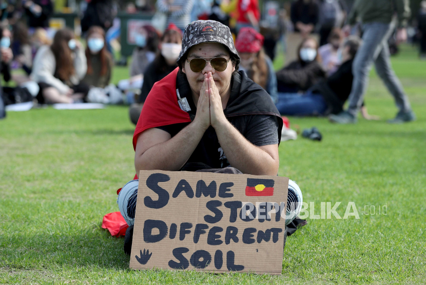 Seorang pengunjuk rasa duduk di sebelah spanduk ketika ia menghadiri rapat umum Black Lives Matter di Langley Park di Perth, Australia, 13 Juni 2020. Protes itu diselenggarakan untuk meningkatkan kesadaran akan kematian orang Aborigin dalam tahanan polisi.