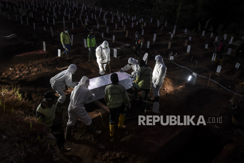 Petugas penggali makam jenazah COVID-19 menurunkan peti ke dalam liang lahat. Makam Covid-19 di Kabupaten Bekasi kerap jadi tempat anak muda berkumpul. Ilustrasi.