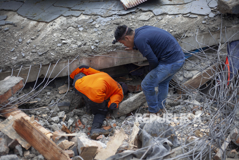  Tim penyelamat mencari korban di antara reruntuhan bangunan yang rusak akibat gempa bumi di Mamuju, Sulawesi Barat, Jumat (15/1/2021). 