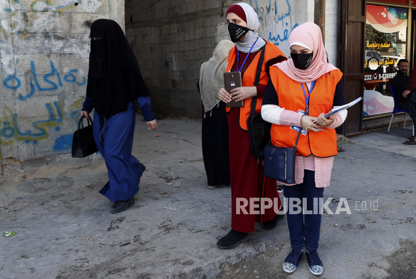  Anggota tim yang mengajukan Komisi Pemilihan Pusat, berjalan untuk mendaftarkan penduduk lokal ke daftar pemilih, di jalan utama Kota Gaza, Rabu (10/2). Petugas pemungutan suara Palestina menyebar di seluruh Jalur Gaza.