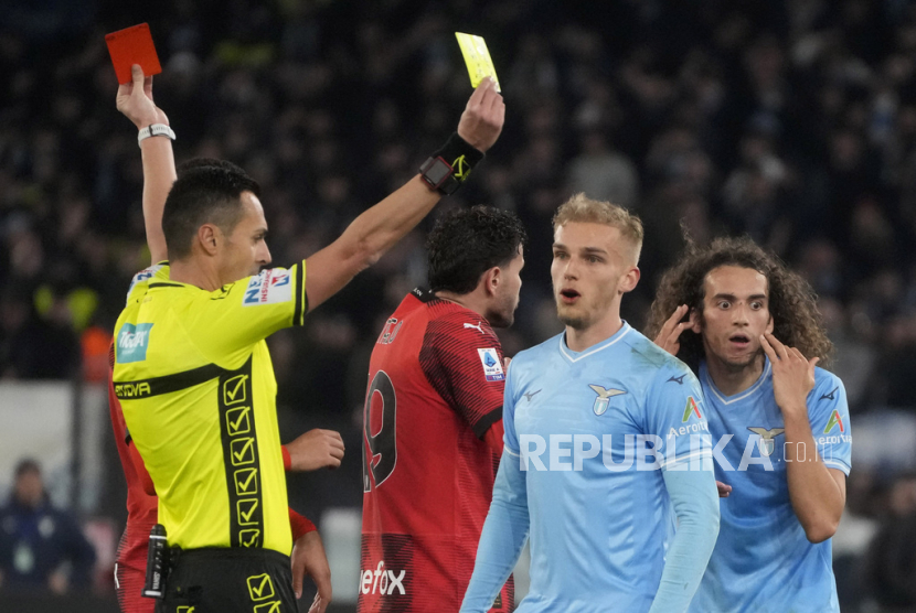 Referee Marco di Bello shows the red card to Lazio Matteo Guendouzi, background right, and the yellow card to AC Milan Christian Pulisic during the Italian Serie A soccer match between Lazio and Milan at Rome Olympic stadium, Friday, March 1, 2024. 