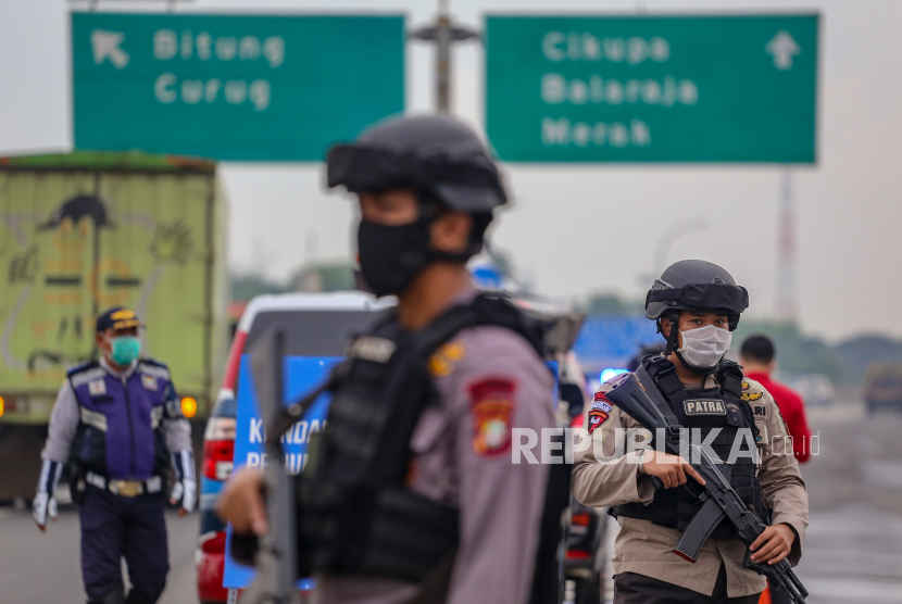 Petugas kepolisian berjaga saat dilakukan penyekatan kendaraan di pintu keluar Tol Bitung, Kabupaten Tangerang, Banten, Jumat (24/4/2020). Penyekatan itu dilakukan menyusul adanya larangan mudik bagi seluruh kalangan yang sudah ditetapkan mulai hari ini guna mencegah penyebaran COVID-19