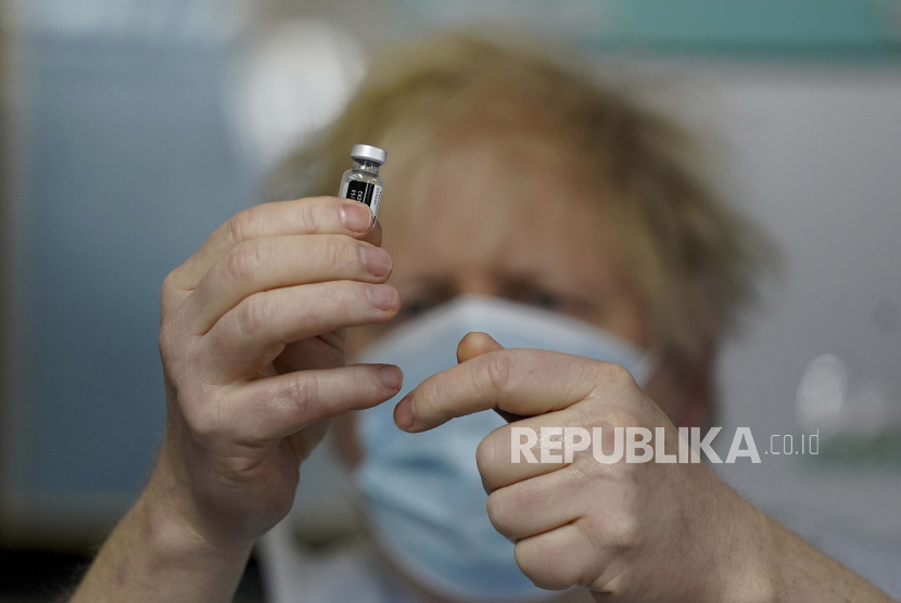 Inggris Siap Salurkan Surplus Vaksin untuk Negara Berkembang. Perdana Menteri Inggris Boris Johnson memegang sebotol vaksin Pfizer BioNTech saat mengunjungi pusat vaksinasi COVID-19 di Batley, West Yorkshire, Inggris, Senin, 1 Febru