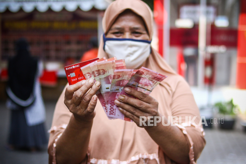 Warga menunjukkan uang bantuan sosial tunai atau BST usai mengambil di ATM Bank DKI, Jakarta, Selasa (20/7/2021). Pemprov DKI menyiapkan anggaran Rp604 miliar untuk bantuan sosial tunai atau BST kepada 1 juta Kepala Keluarga (KK) penerima manfaat selama PPKM darurat. Nilai BST kali ini mencapai Rp600.000 per KK dari hasil rapelan penyaluran tahap 5 dan 6 yang sempat tertunda pada Mei-Juni 2021 lalu. 
