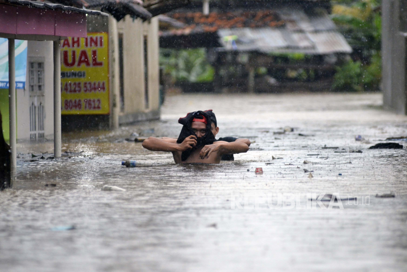 Warga melintasi banjir di Kelurahan Kalibalau Kencana, Kedamaian, Bandar Lampung, Lampung, Rabu (5/8/2020). Banjir yang diakibatkan hujan deras di Kota Bandar Lampung merendam sejumah wilayah akibat buruknya sistem drainase di wilayah tersebut. 