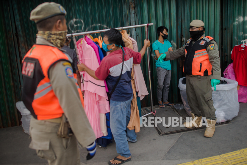 Petugas Satuan Polisi Pamong Praja (Satpol PP) menertibkan sejumlah pedagang pakaian di kawasan Tanah Abang, Jakarta, Ahad (17/5). Penertiban tersebut dilakukan guna mengantisipasi sejumlah pedagang yang tetap berjualan menjelang Hari Raya Idul Fitri meski ada aturan penerapan sosial berskala besar (PSBB) guna mengantisipasi penyebaran pandemi COVID-19