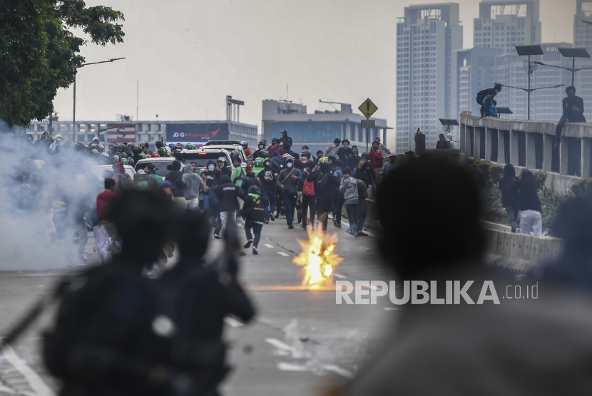 Sejumlah pelajar berlari menghindari gas air mata yang dilepaskan pihak kepolisian saat aksi unjuk rasa di depan kompleks Parlemen di Jakarta, Senin (11/4/2022).  