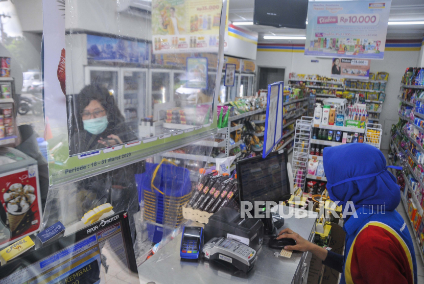 Pembeli melakukan pembayaran dari balik plastik pembatas di salah satu minimarket daerah Bekasi, Jawa Barat, Rabu (8/4/2020). Penggunaan plastik pembatas tersebut bertujuan untuk mengantisipasi penyebaran virus COVID-19
