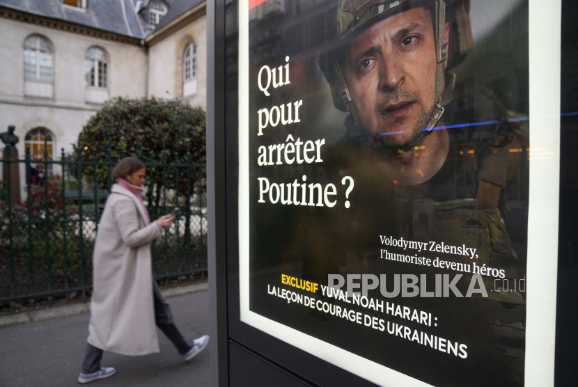 Seorang wanita berjalan di dekat kios koran dengan plakat presiden Ukraina Volodymyr Zelenskyy di halaman depan berjudul Siapa yang harus menghentikan Putin di sebelah katedral Saint Volodymyr Le Grand, di Paris, Prancis, Kamis, 3 Maret 2022.