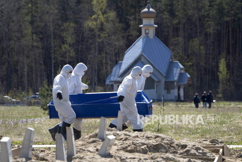Penggali kubur mengenakan pakaian APD membawa peti mati mengubur korban Covid19 pada sebuah kuburan di Kolpino, St. Petersburg, Rusia, Ahad (10/5)