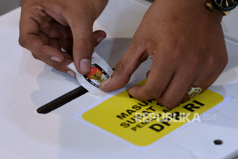 Petugas menempelkan stiker segel kotak suara Pemilu 2024 (ilustrasi). Polda Bali memastika persnelnya siap menjaga 12.809 TPS di Bali.