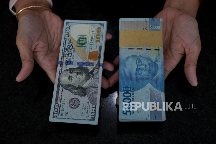 Petugas menunjukan uang dolar AS dan rupiah di tempat penukaran valuta asing PT Valuta Inti Prima di Cikini, Jakarta, Selasa (21/11/2023). 