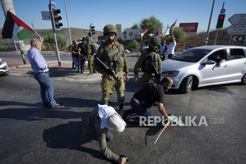 Warga Palestina dan aktivis perdamaian Israel melarikan diri dari gas air mata yang ditembakkan oleh pasukan keamanan Israel, selama demonstrasi menentang pemukiman Yahudi Tepi Barat, dekat kota Salfit, Tepi Barat, Rabu, 27 Juli 2022.