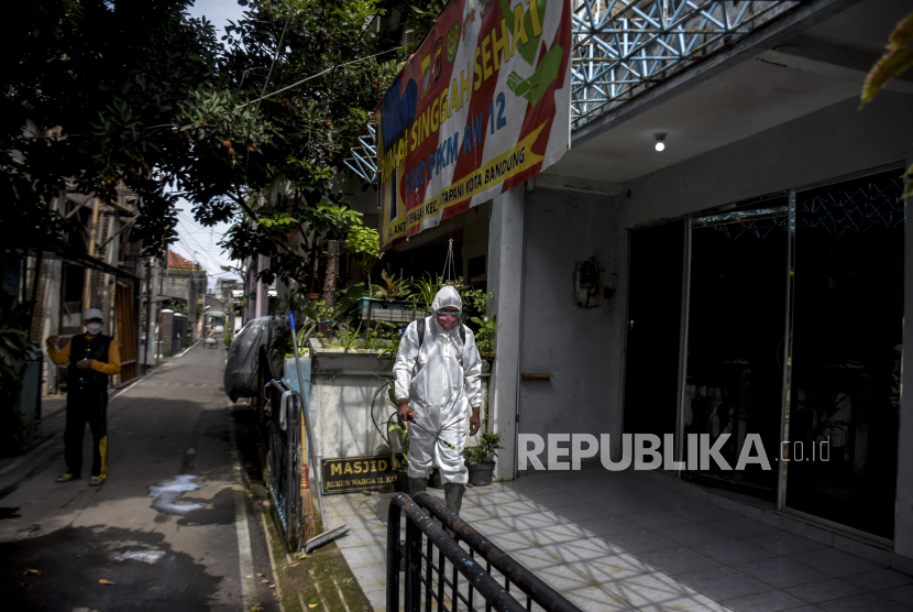 Warga menggunakan alat pelindung diri menyemprotkan cairan disinfektan di area Rumah Singgah Sehat. Kasus aktif COVID-19 yang dirawat di rumah sakit maupun menjalani isolasi mandiri di Kabupaten Karawang, Jawa Barat, semakin berkurang.