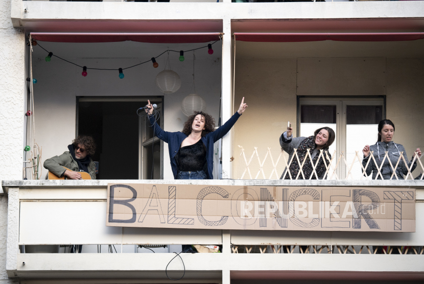 Penyanyi berkebangsaan Swiss Amandine (Rapin) (kedua kiri) melakukan konser singkat di balkonnya saat diberlakukannya keadaan darurat wabah penyakit corona di Lausanne, Swiss, Sabtu (28/3). Negara-negara di seluruh dunia mengambil langkah-langkah pencegahan untuk membendung penyebaran virus corona
