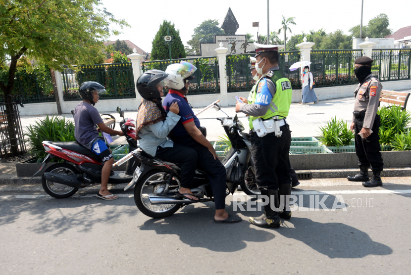 Aparat kepolisian Polresta Yogyakarta mengecek masker pengendara bermotor di perempatan titik nol Yogyakarta, Kamis (23/4). Selain memeriksa dan menghimbau pengendara menggunakan masker, aparat juga membagikan masker bagi pengendara yang tidak memakai