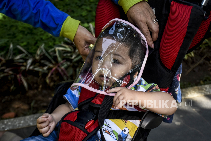 Seorang ibu memasangkan pelindung wajah kepada anaknya saat beraktivitas di Taman Lansia, Jalan Cisangkuy, Kota Bandung, Ahad (21/6). Ruang publik dan taman yang sebelumnya sepi tersebut kembali ramai dikunjungi oleh warga untuk sekedar beraktivitas  ataupun berolahraga di tengah pandemi Covid-19