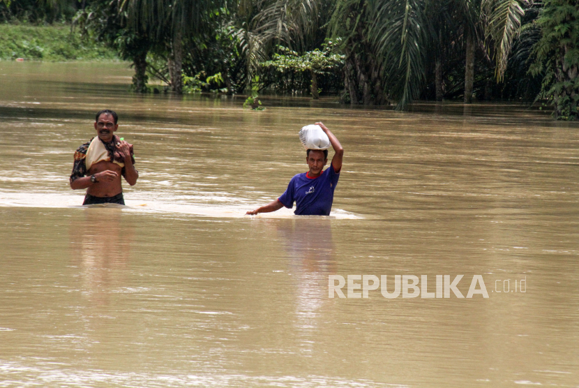 Warga menerobos banjir saat keluar dari permukiman di Desa Lawang, Kecamatan Matang Kuli, Aceh Utara, Aceh, Senin (9/10/2023). Berdasarkan data Badan Penanggulangan Bencana Daerah (BPBD) setempat, Bencana banjir akibat luapan Sungai Krueng Pase, Krueng Pirak, Krueng Keuruto, dan Krueng Peto menyebabkan 6 kecamatan di kabupaten itu terendam banjir, mengakibatkan sekitar 2.864 Kepala Keluarga (KK) dengan 9.755 jiwa terdampak banjir, sebanyak 1.726 jiwa mengungsi. 