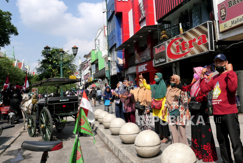 Pedagang dan wisatawan menyambut iring-iringan kendaraan memutar lagu Garuda Pancasila di kawasan wisata Jalan Malioboro, Yogyakarta, Selasa (1/6). Dalam rangka memperingati Hari Lahir Pancasila beberapa elemen masyarakat di Malioboro melakukan penghormatan saat pemutaran Lagu Indonesia Raya. Selanjutnya, memutar lagu Garuda Pancasila dan berjalan di sepanjang Jalan Malioboro. Pedagang, tukang becak, kusir andong, dan wisatawan juga ikut berdiri menyambut pemutaran lagu kebangsaan.