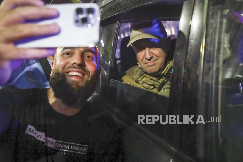Yevgeny Prigozhin, the owner of the Wagner Group military company, right, sits inside a military vehicle posing for a selfie photo with a local civilian on a street in Rostov-on-Don, Russia, Saturday, June 24, 2023, prior to leaving an area of the headquarters of the Southern Military District. Kremlin spokesman Dmitry Peskov said that Prigozhin