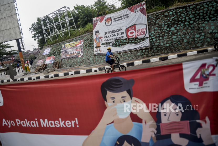 Pesepeda melintas di dekat spanduk sosialisasi Pemilihan Kepala Daerah (Pilkada) yang terpasang di kawasan Serpong, Tangerang Selatan, Banten, Senin (28/9).