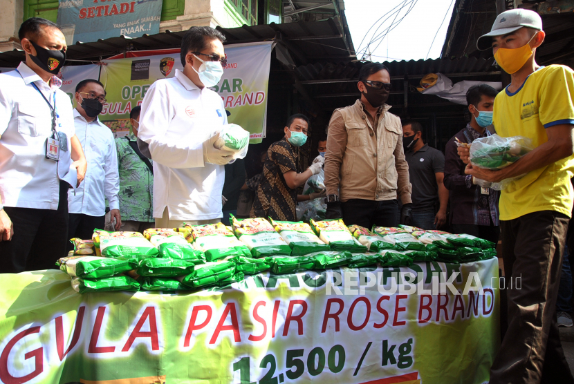 Menteri Perdagangan Agus Suparmanto (ketiga kiri) bersama Wali Kota Bogor Bima Arya (keempat kanan) membagikan gula pasir saat operasi pasar gula pasir di Pasar Baru Bogor, Jawa Barat, Ahad (17/5/2020). Operasi pasar dengan menjual gula pasir dengan harga Rp12