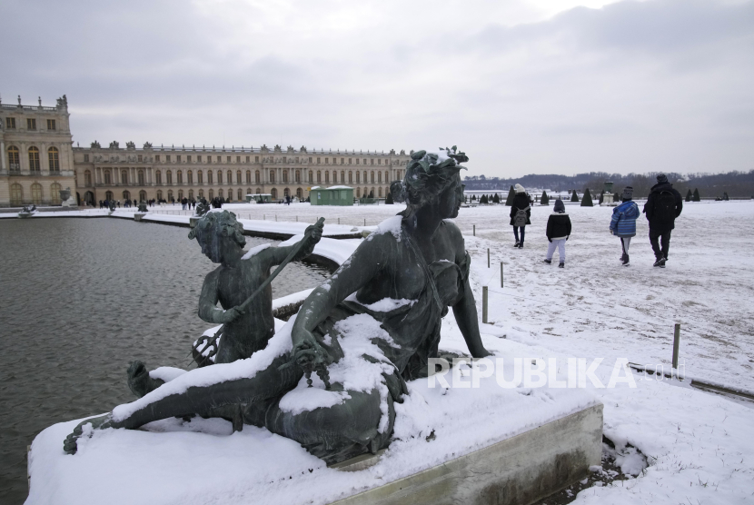 Wisatawan berjalan di dekat patung yang tertutup salju di Chateau de Versailles, Paris, Selasa (9/1/2024). Cuaca dingin ekstrem terjadi di Prancis, di mana suhu turun di bawah nol derajat Celsius (32 derajat Fahrenheit). Salju juga tampak menutupi sejumlah wilayah di Paris, Prancis.