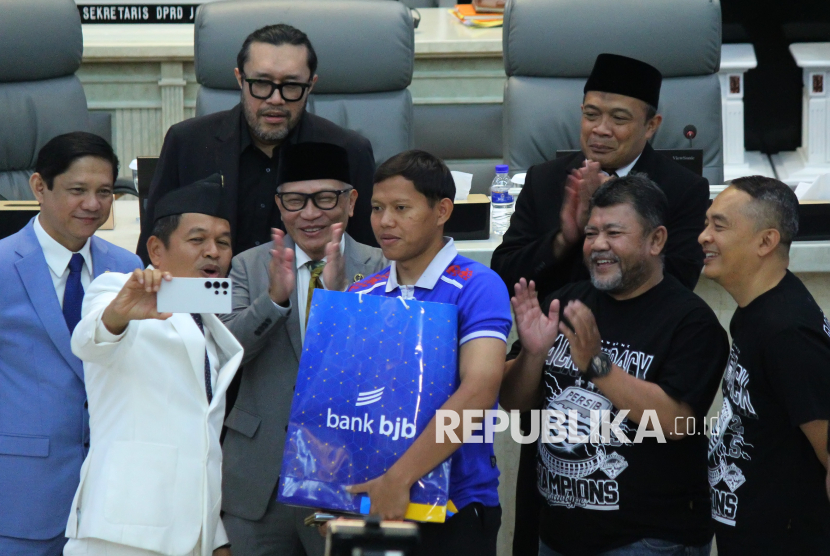 Gubernur Jawa Barat (Jabar) Dedi Mulyadi membuat konten sosial media bersama pemain persib dan ketua DPRD serta wakil DPRD Jabar saat penyerahan uang bonus atau kadeudeuh kepada pemain Persib yang diwakili Adam Alis usai rapat paripurna DPRD Jabar, di Gedung DPRD Jabar, Jalan Diponegoro, Kota Bandung, Senin (26/5/2025). Sebelumnya diberitakan, Gubernur Jabar menjanjikan bonus sebesar Rp 2 miliar kepada Persib Bandung sebaga juara di Liga 1 musim 2024-2025. Bonus tersebut berasal dari saku pribadi Dedi Mulyadi sebesar Rp 1 miliar dan sisanya berasal dari sumbangan pribadi para pejabat Pemprov Jabar secara sukarela.