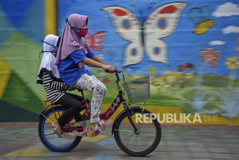 Dua orang anak menggunakan masker saat bermain sepeda di Ampenan, Mataram, NTB, Kamis (28/5/2020). Menurut data Dinas Kesehatan Provinsi NTB per 26 Mei 2020, jumlah anak-anak di NTB yang positif tertular Covid-19 sebanyak 86 orang dengan rincian 35 balita dan 51 anak (usia 6-18 tahun) yang sebagian besar tertular dari keluarga dekat.