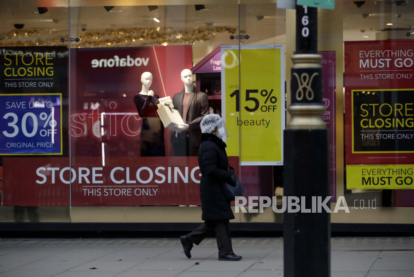 Seorang wanita yang mengenakan pelindung wajah dan masker untuk menahan penyebaran virus corona berjalan melewati department store Debenhams, yang sedang dalam proses ditutup, di Oxford Street, di London. (ilustrai).