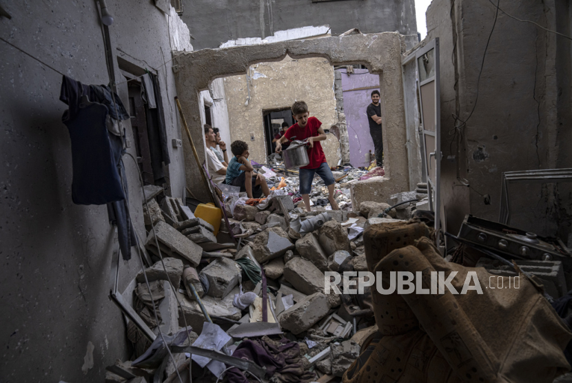 Warga Palestina memeriksa puing-puing sebuah rumah setelah terkena serangan udara Israel di Khan Younis, Jalur Gaza selatan, Ahad, (29/10/2023). 
