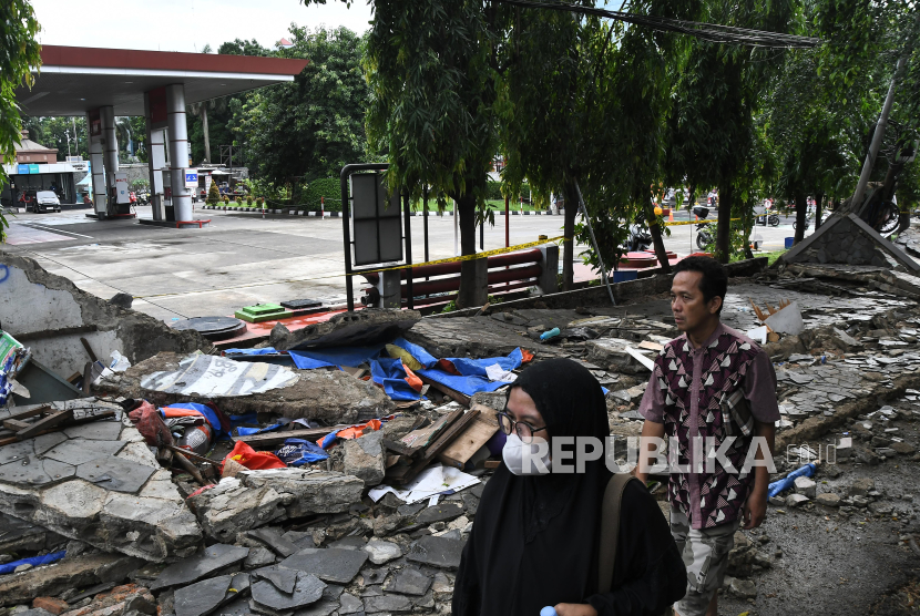 Sejumlah warga melintas di dekat tembok yang roboh di Jalan Tebet Timur Dalam, Jakarta Selatan, Ahad (21/1/2024). Menurut warga, kejadian tembok roboh yang menimpa gerobak pedagang pada pukul 12.15 WIB itu mengakibatkan tiga orang meninggal dunia dan satu orang luka-luka. 