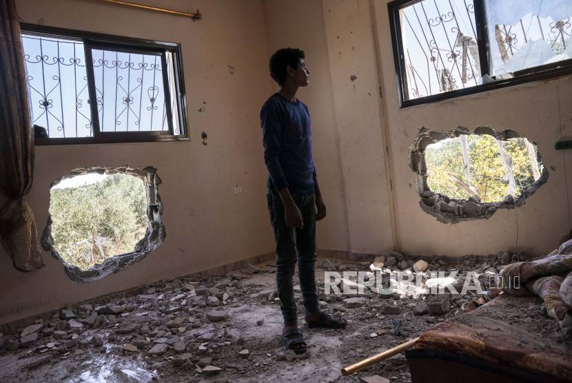  Issat Al-Masri, 18, berdiri untuk potret di kamar tidurnya yang dirusak oleh penembakan sebelum gencatan senjata yang menghentikan perang 11 hari antara penguasa Hamas Gaza dan Israel, Rabu, 26 Mei 2021, di Beit Hanoun, Jalur Gaza.