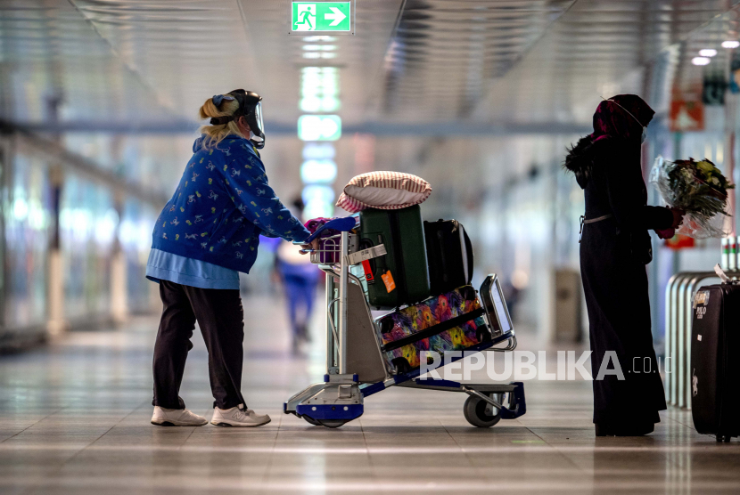 Seorang wanita yang memakai pelindung wajah pergi ke tempat parkir di bandara di Frankfurt, Jerman, Selasa, 30 Maret 2021.