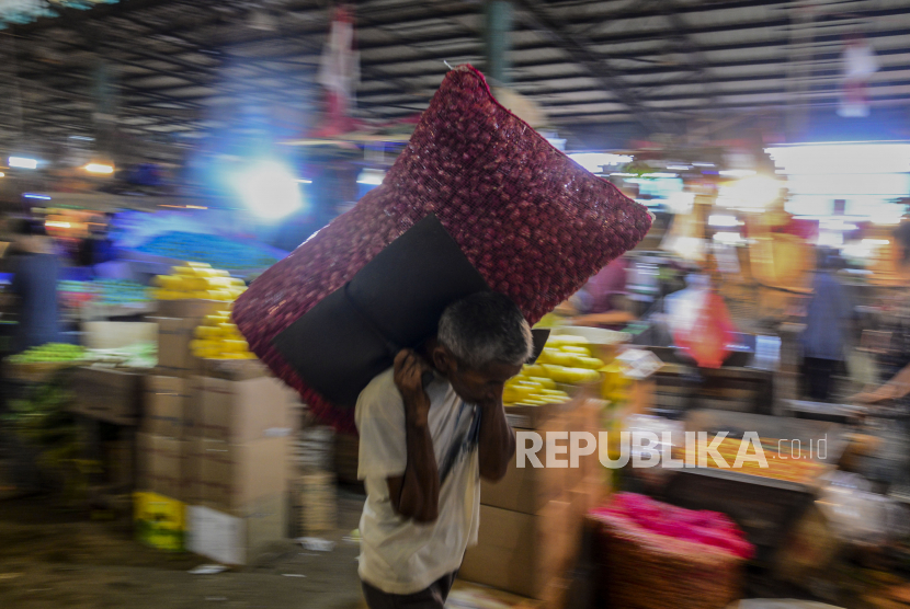 Pedagang membawa bawang di pasar tradisional.