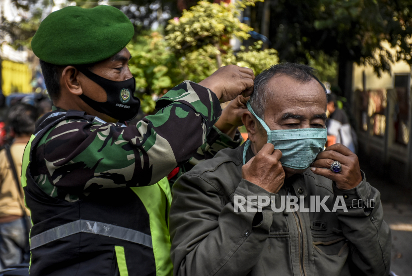 Anggota TNI memasangkan masker kepada pengendara motor saat Operasi Yustisi Peningkatan Disiplin dan Penegakan Hukum Protokol Covid-19  (ilustrasi)
