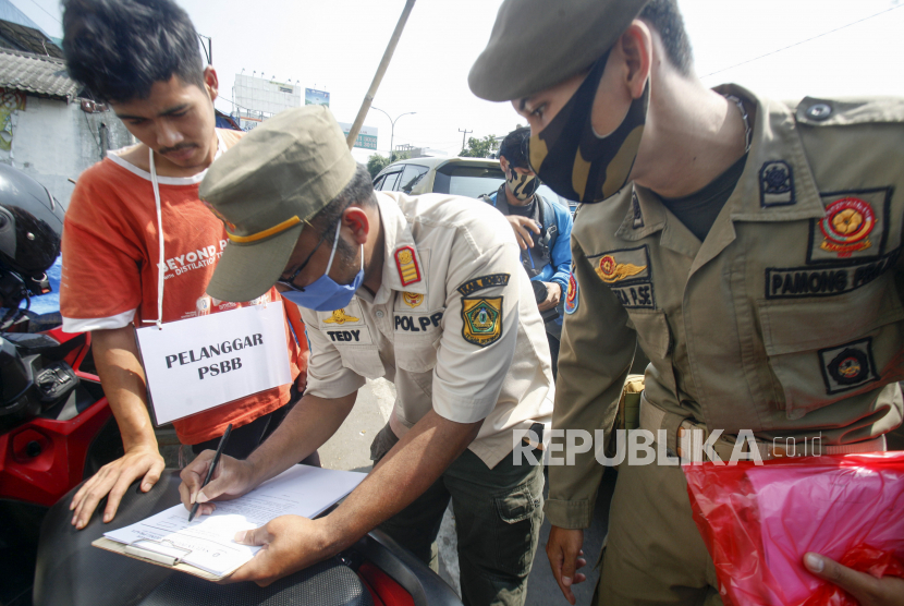 Petugas Satpol PP menilang warga yang tidak menggunakan masker di kawasan Pasar Cibinong, Kabupaten Bogor, Jawa Barat.