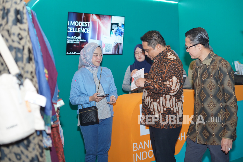 Direktur Sales & Distribution BSI Anton Sukarna (kedua kiri) berbincang dengan salah satu pengunjung Jakarta Muslim Fashion Week 2024 di ICE BSD, Jumat (20/10/2023).