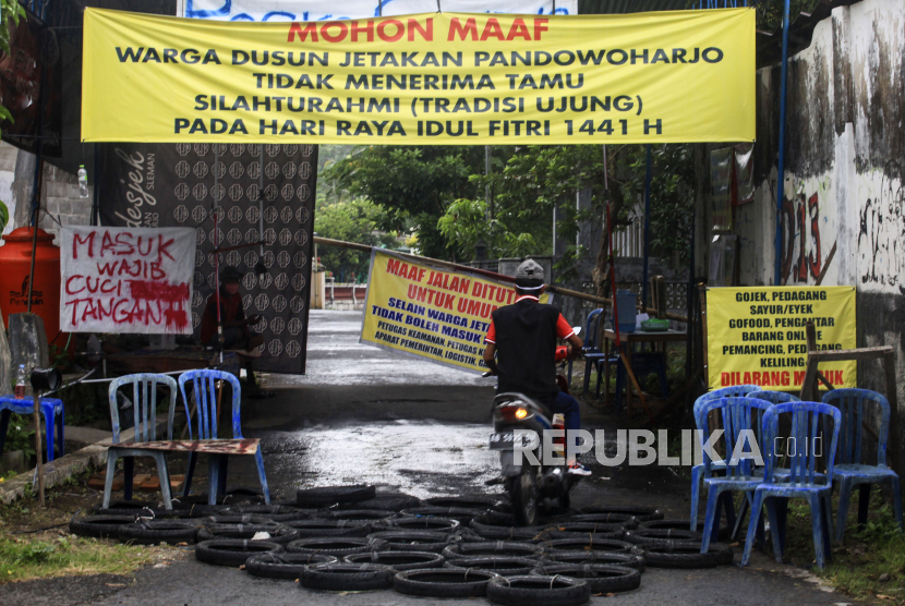 Warga melintasi pintu masuk kampung yang ditutup di Pandowoharjo, Sleman, Daerah Istimewa Yogyakarta (DIY), Selasa (26/5/2020). Sebagian kampung di DIY saat Idul Fitri 2020 ini tidak menerima tamu sebagai upaya pencegahan penyebaran COVID-19is